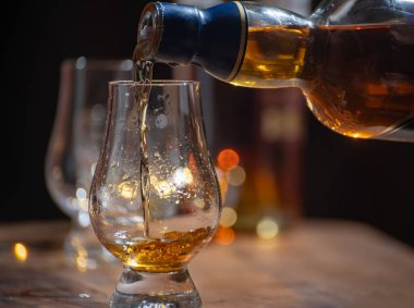 Viski dökülüyor, bir bardak viski ve karışık viski Edinburgh, İskoçya 'daki barda servis ediliyor ve arka planda parti ışıkları var.