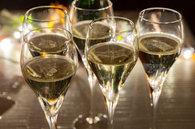 Yeni yıl partisi, küçük brut şampanya baloncukları kava ya da lale gözlüklü şarap koyu arka planda çelenk ışıkları