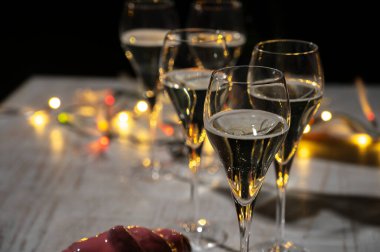 Yeni yıl partisi, küçük brut şampanya baloncukları kava ya da lale gözlüklü şarap koyu arka planda çelenk ışıkları