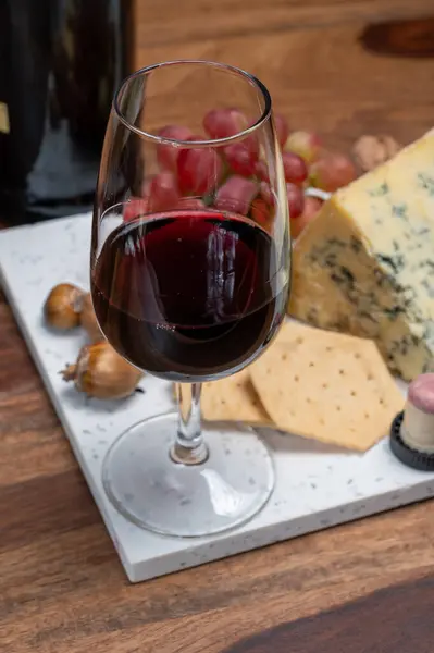 Red porto and cheese pairing, blue matured stilton English cheese served as dessert with walnuts and glass ruby porto wine close up