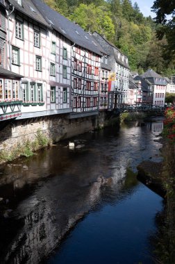 Nehrin kıvrımlarındaki eski renkli Alman şehri Monschau 'nun evleri ve caddeleri görünüyor ve tepelerin arasında saklanıyor, Eifel Ulusal Parkı, Almanya yazın.