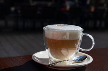 Açık kafede kremşantili sütlü taze İtalyan kahvesi içiyorum.