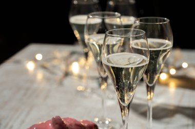 Yeni yıl partisi, küçük brut şampanya baloncukları kava ya da lale gözlüklü şarap koyu arka planda çelenk ışıkları