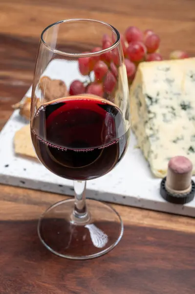 Red porto and cheese pairing, blue matured stilton English cheese served as dessert with walnuts and glass ruby porto wine close up