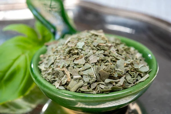 Dried crushed and whole fresh leaves of green aromatic basil plant used for cooking and medicine close up