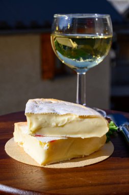 Reblochon Fransız peyniri Haute-Savoie 'de, beyaz Roussette de Savoie ya da Vin de Savoie şarabı eski Alripne köyü manzaralı ve Hautes Alpes dağları yazın karla kaplı..