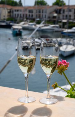 Fransız brüt şampanyası bardaklarda köpüklü şarap içmek, Saint-Tropez yakınlarındaki Port Grimaud limanında kulüp partisi, Fransız Riviera tatili, Var, Fransa