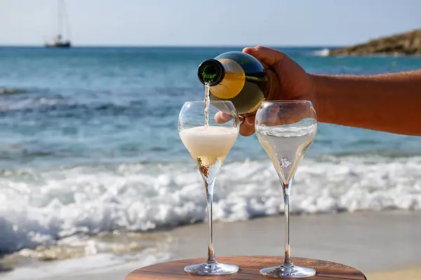 Summer time in Provence, two glasses of cold champagne cremant sparkling wine on sandy beach near Saint-Tropez in sunny day, Var department, vacation in France