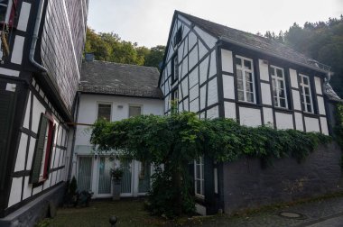 Nehrin kıvrımlarındaki eski renkli Alman şehri Monschau 'nun evleri ve caddeleri görünüyor ve tepelerin arasında saklanıyor, Eifel Ulusal Parkı, Almanya yazın.