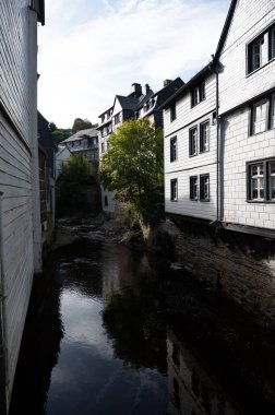 Nehrin kıvrımlarındaki eski renkli Alman şehri Monschau 'nun evleri ve caddeleri görünüyor ve tepelerin arasında saklanıyor, Eifel Ulusal Parkı, Almanya yazın.