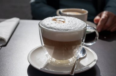 Açık kafede kremşantili sütlü taze İtalyan kahvesi içiyorum.