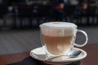 Açık kafede kremşantili sütlü taze İtalyan kahvesi içiyorum.