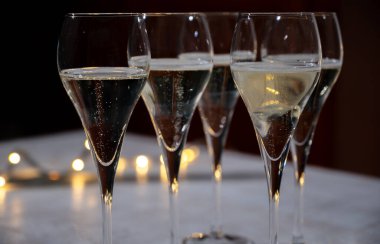 Yeni yıl partisi, küçük brut şampanya baloncukları kava ya da lale gözlüklü şarap koyu arka planda çelenk ışıkları