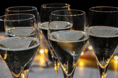 Yeni yıl partisi, küçük brut şampanya baloncukları kava ya da lale gözlüklü şarap koyu arka planda çelenk ışıkları