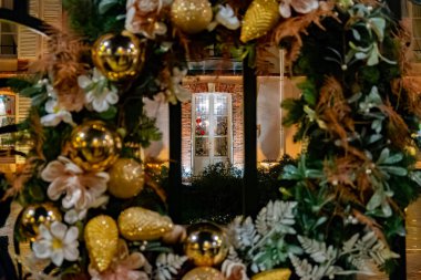 Noel ve Yeni Yıl sokak dekorasyonu, metal kapıda asılı duran yuvarlak Noel çelengi, geceleri aydınlatılmış cam kapı, Fransa, Şampanya 'da Epernay.