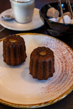 Fransa 'nın Bordeaux bölgesinin spesiyali olan rom ve vanilyalı Fransız pastası Canele, Fransız restoranında bir fincan siyah kahveyle beyaz tabakta servis edilir.