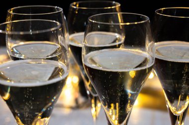 Yeni yıl partisi, küçük brut şampanya baloncukları kava ya da lale gözlüklü şarap koyu arka planda çelenk ışıkları