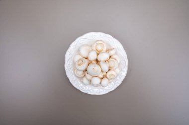 Beyaz şampiyon mantarları taze pişmemiş beyaz seramik plaka fotokopi alanı gri arka planda