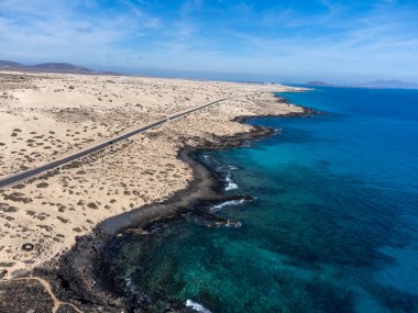 Corralejo sahili yakınlarındaki beyaz kumlu kumsallarda, siyah asfalt yolda araba sürmek Fuerteventura, Kanarya Adaları, İspanya kışın