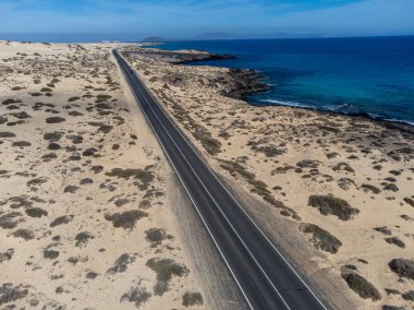 Corralejo sahili yakınlarındaki beyaz kumlu kumsallarda, siyah asfalt yolda araba sürmek Fuerteventura, Kanarya Adaları, İspanya kışın