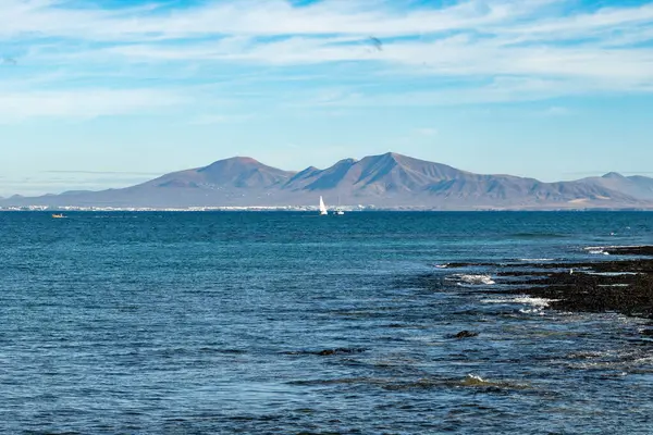 Beyaz mercanlar, siyah kayalar, mavi sular, Fuerteventura, Kanarya adaları, İspanya 'nın beyaz patlamış mısır plajı boyunca Corralejo kasabasında deniz gezintisi.