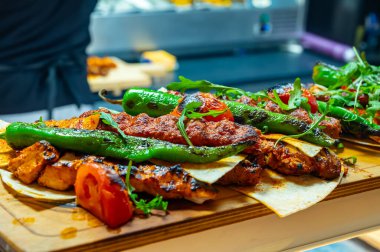 İstanbul 'daki lokantada mangal kömürü ızgarasından ahşap tabak, ızgara et, tavuk kanadı, kuzu eti, şiş kebap, biber.