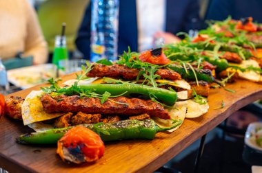 İstanbul 'daki lokantada mangal kömürü ızgarasından ahşap tabak, ızgara et, tavuk kanadı, kuzu eti, şiş kebap, biber.