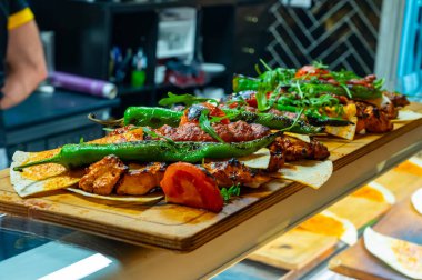 İstanbul 'daki lokantada mangal kömürü ızgarasından ahşap tabak, ızgara et, tavuk kanadı, kuzu eti, şiş kebap, biber.