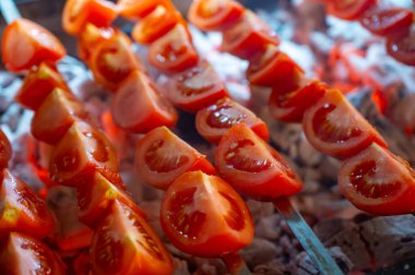 Türk restoranındaki kömür ızgarasının üstünde olgun kırmızı domatesli barbekü.