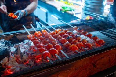 Türk restoranındaki kömür ızgarasının üstünde olgun kırmızı domatesli barbekü.