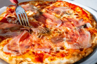 İtalyan pizzacıda peynirli ve Prosciutto di Parma 'lı taze fırında pizza yemek.