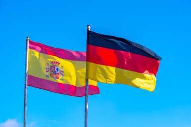 Flagstaff ve mavi gökyüzünde İspanyol ve Alman bayrakları kopyalama alanı