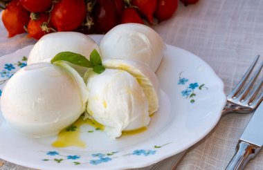 Cheese collection, white balls of soft Italian cheese mozzarella, served with olive oil, tomatoes, fresh basil leaves close up clipart