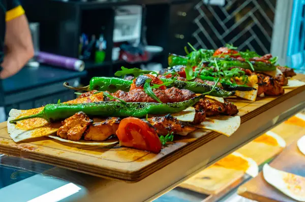 İstanbul 'daki lokantada mangal kömürü ızgarasından ahşap tabak, ızgara et, tavuk kanadı, kuzu eti, şiş kebap, biber.