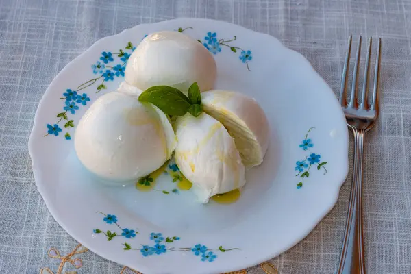 Peynir koleksiyonu, beyaz İtalyan peynirli mozzarella topları zeytin yağı ve taze fesleğen yapraklarıyla servis ediliyor.