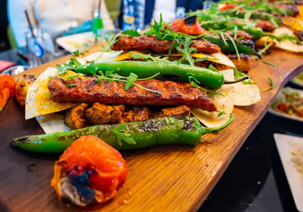İstanbul 'daki lokantada mangal kömürü ızgarasından ahşap tabak, ızgara et, tavuk kanadı, kuzu eti, şiş kebap, biber.