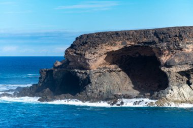 West coast of Fuerteventura island. View on blue water and black volcanic caves of Ajuy village, Canary islands, Spain. clipart