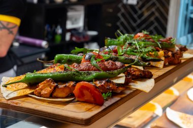 İstanbul 'daki lokantada mangal kömürü ızgarasından ahşap tabak, ızgara et, tavuk kanadı, kuzu eti, şiş kebap, biber.