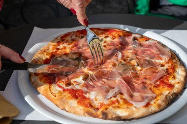İtalyan pizzacıda peynirli ve Prosciutto di Parma 'lı taze fırında pizza yemek.