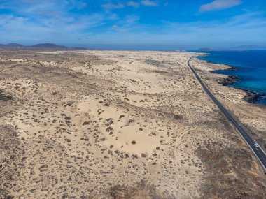Corralejo sahili yakınlarındaki beyaz kumlu kumsallarda, siyah asfalt yolda araba sürmek Fuerteventura, Kanarya Adaları, İspanya kışın