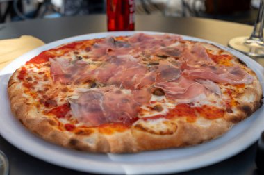 İtalyan pizzacıda peynirli ve Prosciutto di Parma 'lı taze fırında pizza yemek.