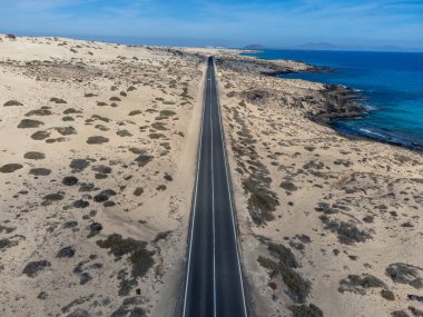 Corralejo sahili yakınlarındaki beyaz kumlu kumsallarda, siyah asfalt yolda araba sürmek Fuerteventura, Kanarya Adaları, İspanya kışın