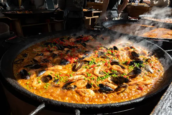 Street food in London, food court on Portobello road Saturday market, fresh prepared colorful paella with rice and sea food in big pan, ready to eat