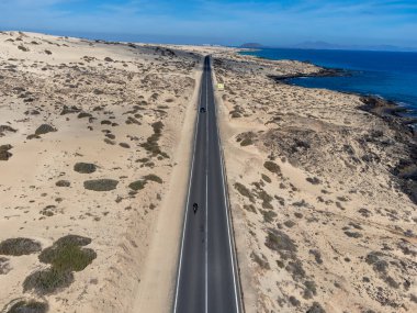 Corralejo sahili yakınlarındaki beyaz kumlu kumsallarda, siyah asfalt yolda araba sürmek Fuerteventura, Kanarya Adaları, İspanya kışın