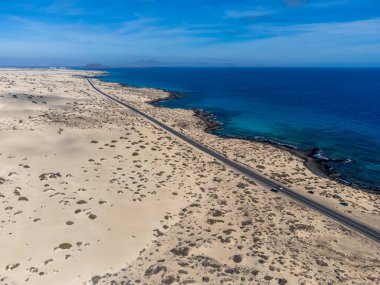 Corralejo sahili yakınlarındaki beyaz kumlu kumsallarda, siyah asfalt yolda araba sürmek Fuerteventura, Kanarya Adaları, İspanya kışın
