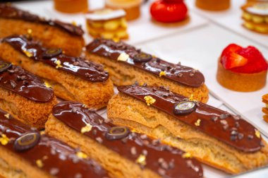 Çeşitli tatlı kekler çikolatalı ekler, krema, kırmızı meyveler ve kremalı turtalar.