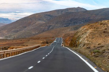 Betancuria Massif, Fuerteventura, Kanarya Adaları, İspanya 'nın renkli uzak bazal tepeleri ve dağları üzerindeki dağ asfalt yolu.