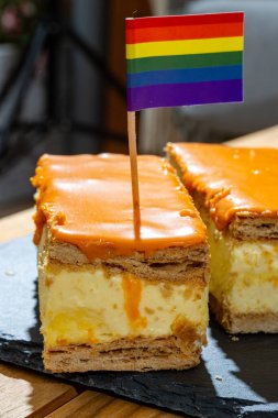 Celebration of the King birthday in Netherlands, tompoes or tompouce, iconic pastry in Netherlands made from puff dough, orange icing, cream and rainbow lgbt pride flags clipart