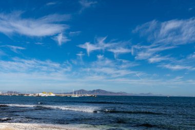 Corralejo 'da deniz gezinti güvertesinde yürürken siyah kayalar, mavi su, volkanik Lanzarote adası manzarası, Fuerteventura, Kanarya adaları, İspanya