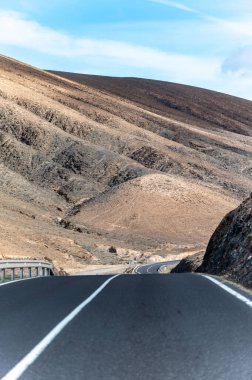 Betancuria Massif, Fuerteventura, Kanarya Adaları, İspanya 'nın renkli uzak bazal tepeleri ve dağları üzerindeki dağ asfalt yolu.